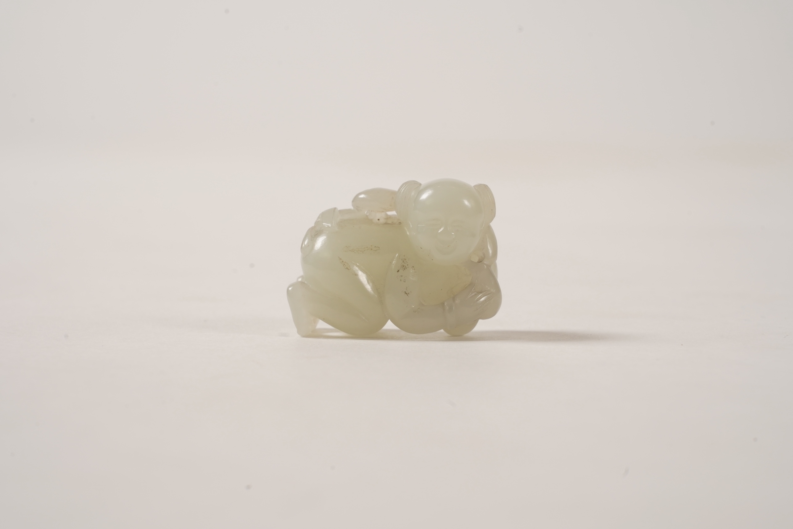 A Chinese white jade figure of a crouching boy, 19th/20th century